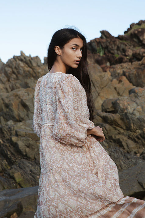 Daughters of India Jasmine Midi Dress in Shell — over-shoulder glance on coastal rocks, balloon sleeve detail